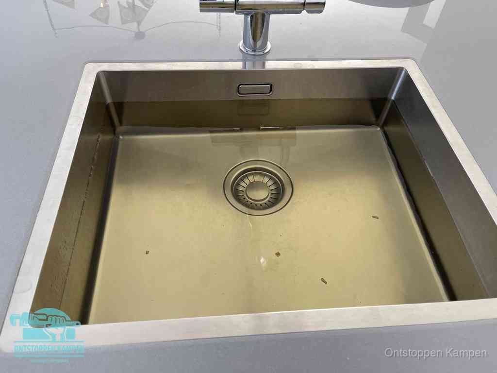 Stilstaand water in een rvs spoelbak dat niet wegloopt, een duidelijk signaal van een gootsteenverstopping in Kampen