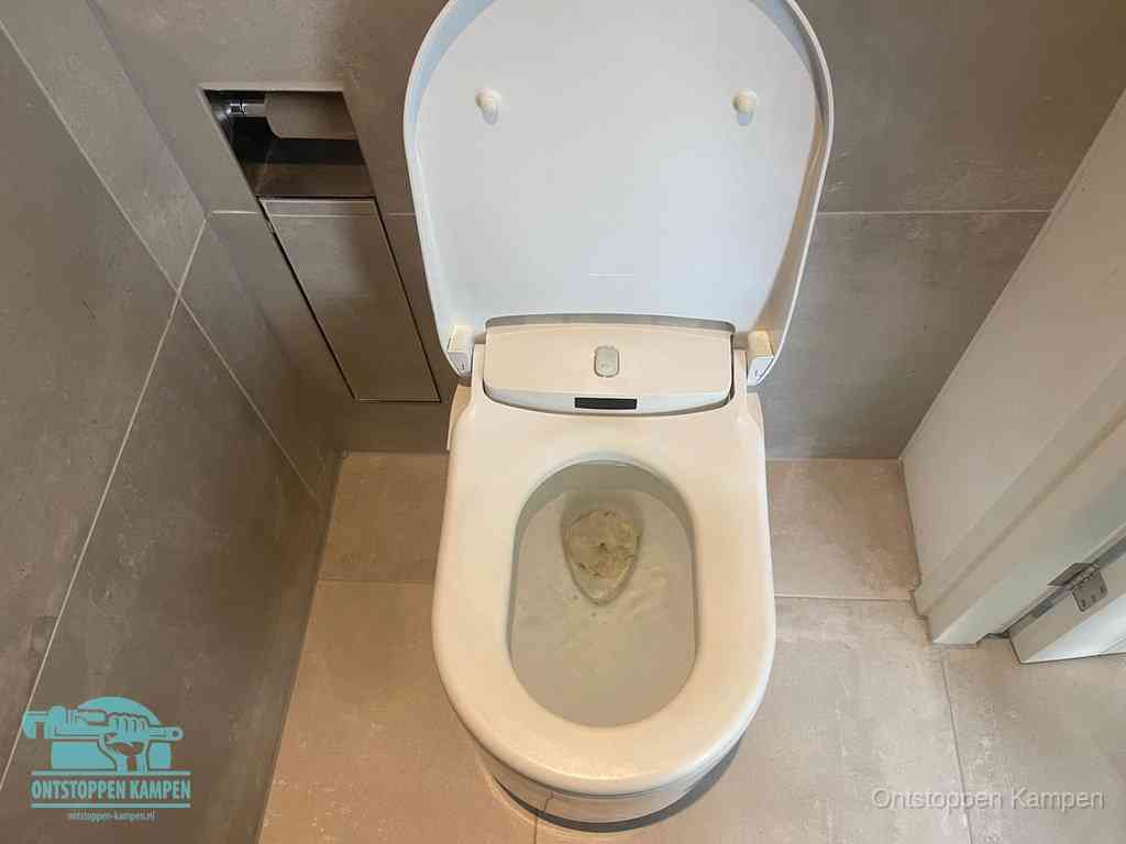 Een wit hangtoilet waarin een prop wc-papier op het water blijft drijven, een duidelijk signaal van een verstopte wc in Kampen