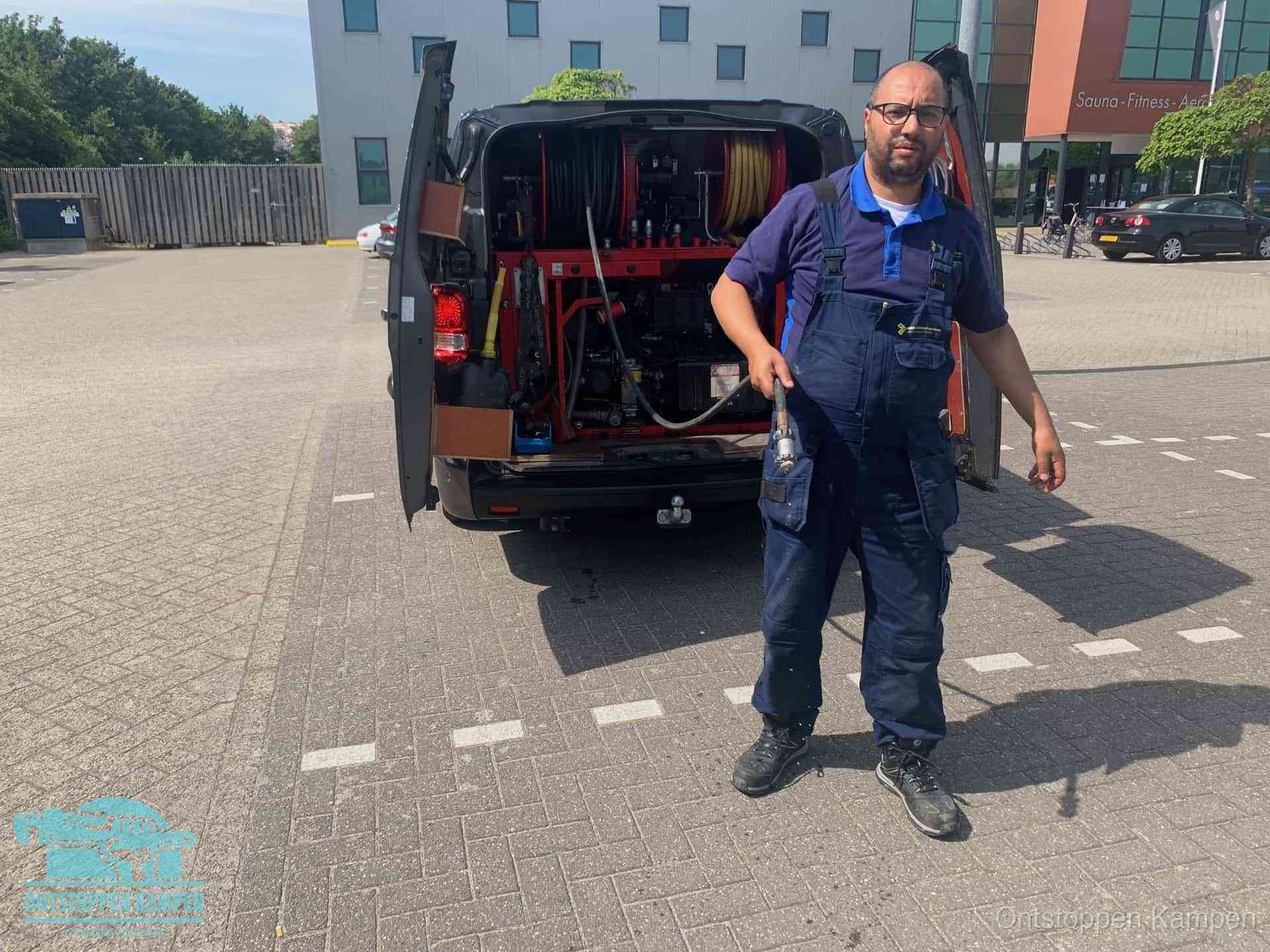 Een monteur bij zijn bestelbus met een hogedruk- en rioolreinigingsunit, klaar om de oorzaak van terugkerende wc-verstoppingen aan te pakken in Kampen