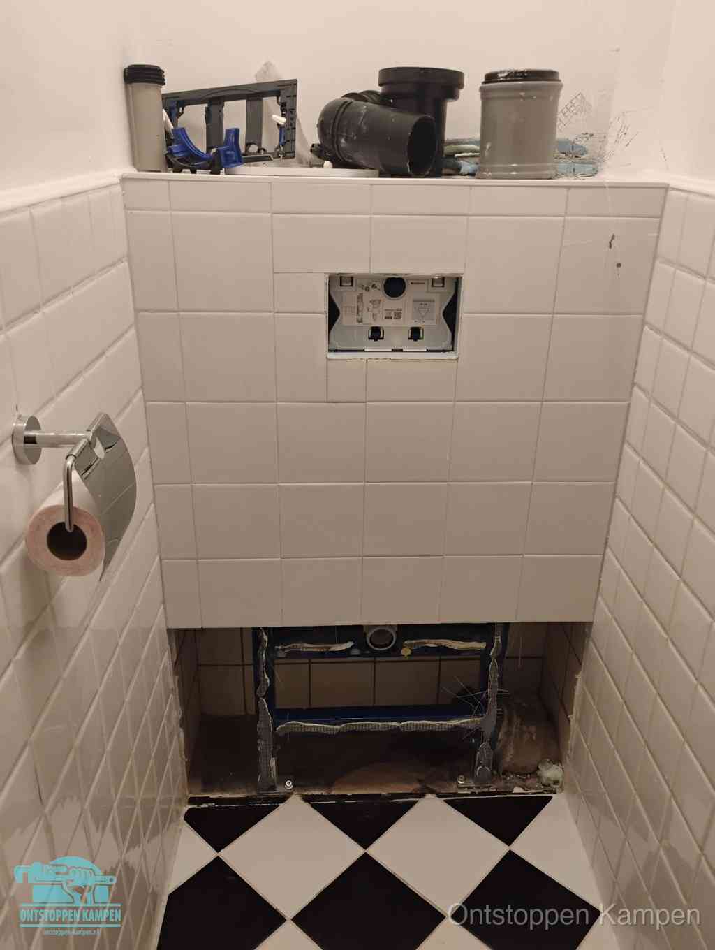 Een toiletruimte waar het hangtoilet en de inbouwreservoir-onderdelen zijn vrijgelegd voor onderhoud, periodiek nazicht voorkomt een wc-verstopping in Kampen